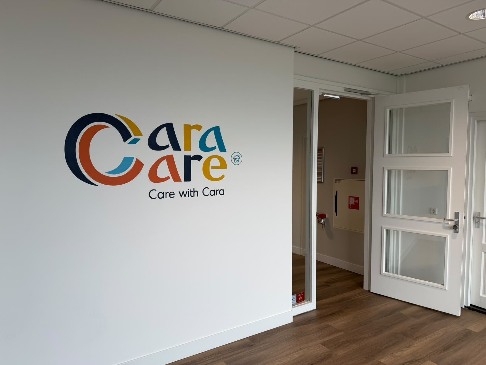Het logo van Cara Care op de muur van het kantoor in Schiedam