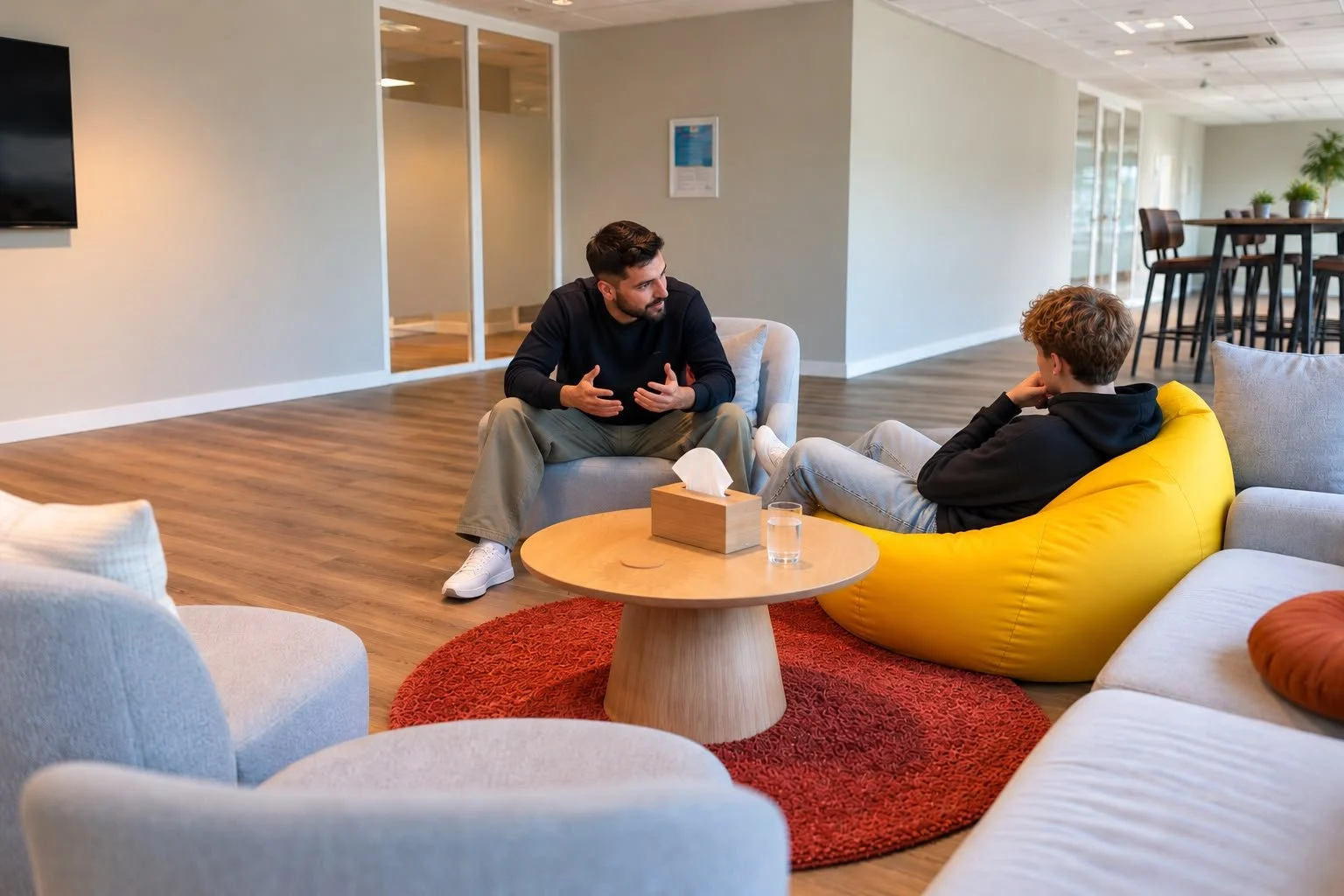 Een behandelaar in gesprek met een jongere in de lounge