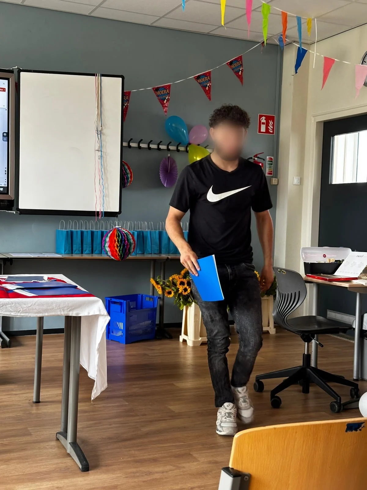 Een jongere van Cara Care loopt met zijn diploma door een versierd klaslokaal